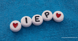 Blue background with small beads that spell out IEP. Beads on the end have red hearts.